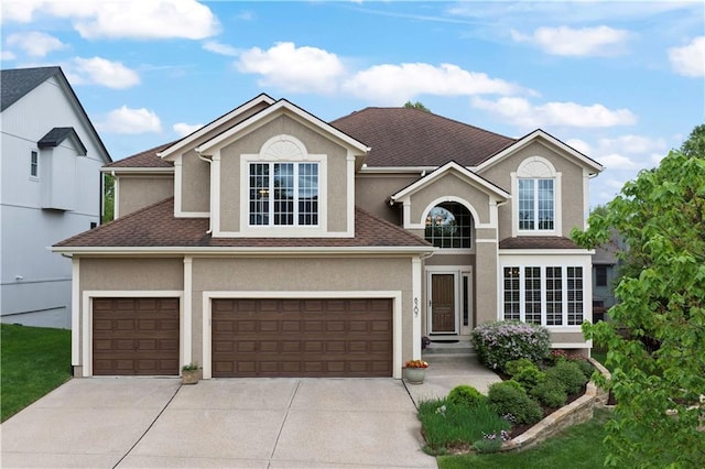 traditional-style house featuring a garage, stucco siding, driveway, and a shingled roof