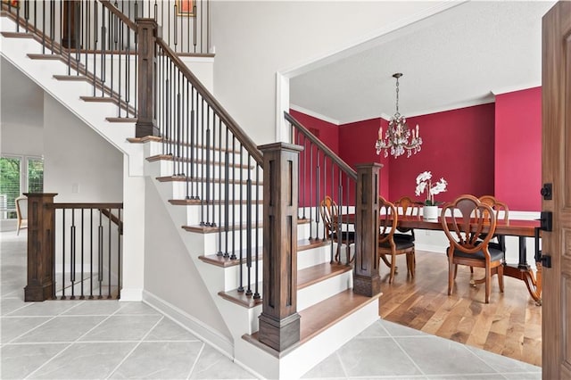 staircase featuring tile patterned floors, baseboards, a high ceiling, and a chandelier