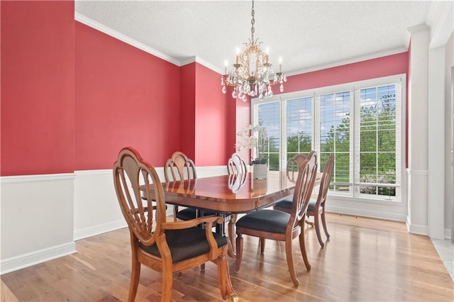 dining room with crown molding, a textured ceiling, a chandelier, baseboards, and wood finished floors