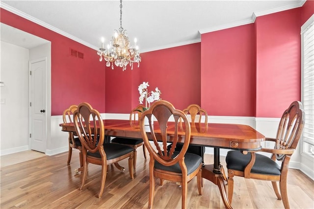dining space featuring visible vents, crown molding, an inviting chandelier, wood finished floors, and baseboards