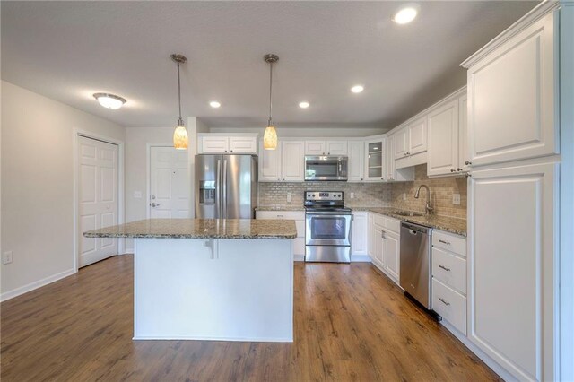 kitchen with a sink, white cabinetry, a kitchen island, and stainless steel appliances
