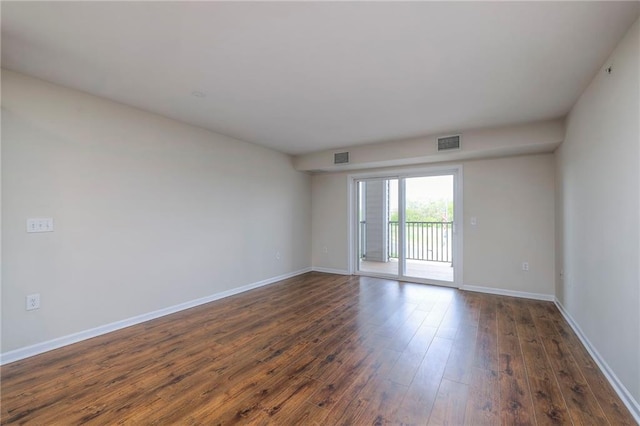 spare room featuring baseboards, visible vents, and dark wood finished floors
