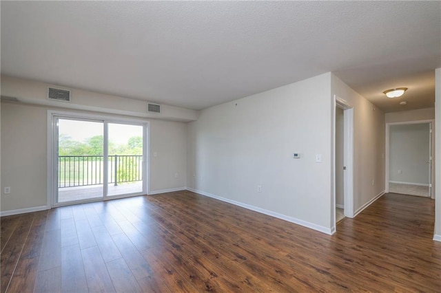 empty room with visible vents, baseboards, and dark wood-type flooring