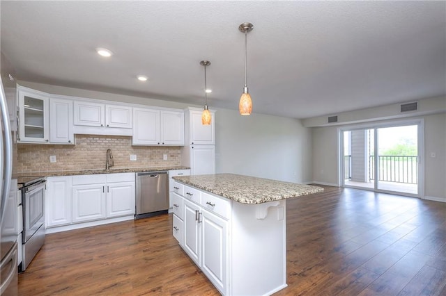 kitchen with appliances with stainless steel finishes, a sink, a center island, decorative backsplash, and visible vents