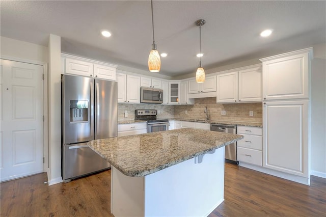 kitchen featuring white cabinets, backsplash, stainless steel appliances, and light stone countertops
