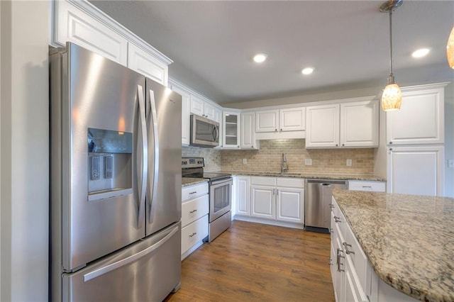 kitchen featuring white cabinets, a sink, appliances with stainless steel finishes, backsplash, and decorative light fixtures