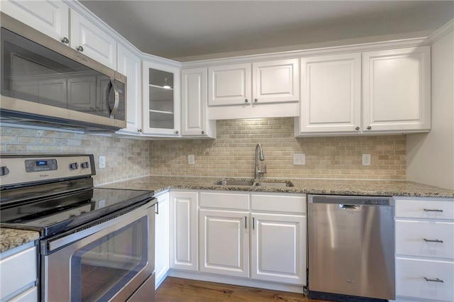 kitchen featuring decorative backsplash, stainless steel appliances, white cabinetry, and a sink