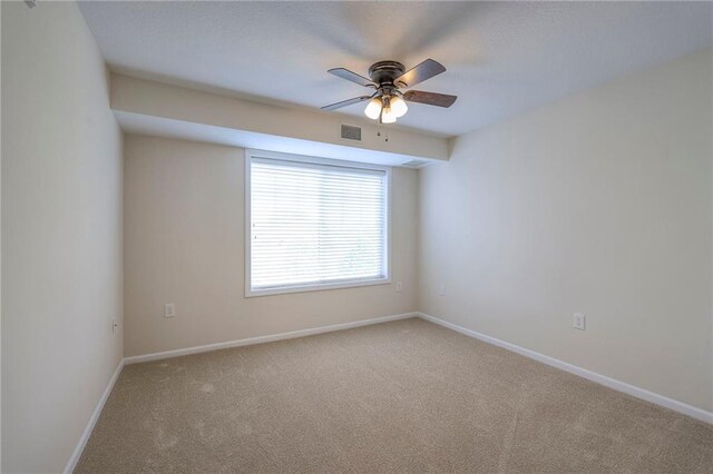 carpeted spare room with baseboards, a ceiling fan, and visible vents