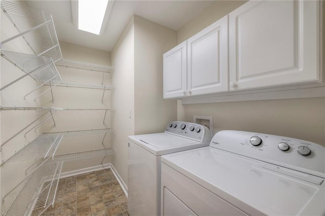 clothes washing area featuring baseboards, stone finish flooring, cabinet space, and washer and dryer
