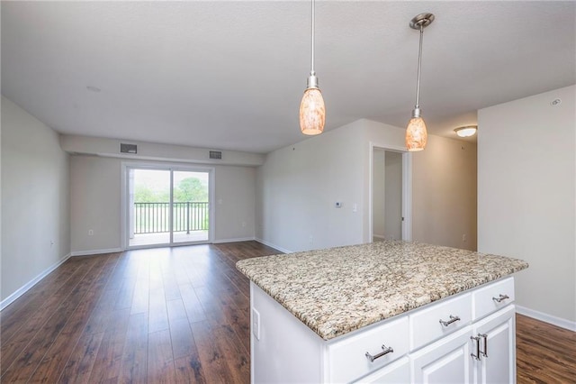 kitchen with dark wood-style flooring, a center island, hanging light fixtures, light stone countertops, and baseboards