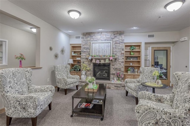 living area with carpet floors, a stone fireplace, a textured ceiling, and visible vents