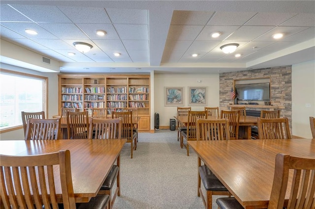 dining space with visible vents, a drop ceiling, and light carpet