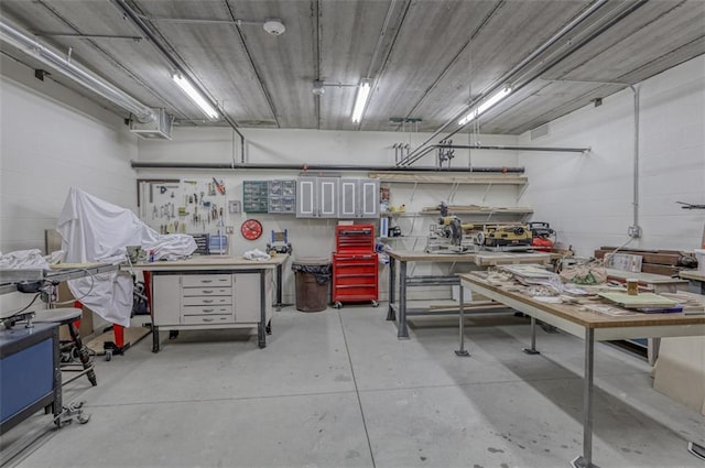 miscellaneous room featuring concrete block wall, a workshop area, and concrete floors