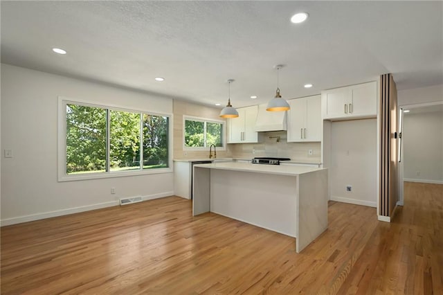 3907 Scherer Rd, Lees Summit, MO 64082 - kitchen with visible vents, light countertops, white cabinets, custom range hood, and a sink