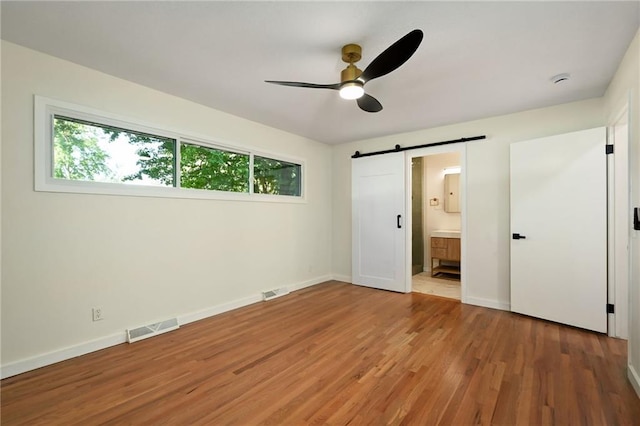 3907 Scherer Rd, Lees Summit, MO 64082 - unfurnished bedroom with wood finished floors, baseboards, a barn door, and visible vents