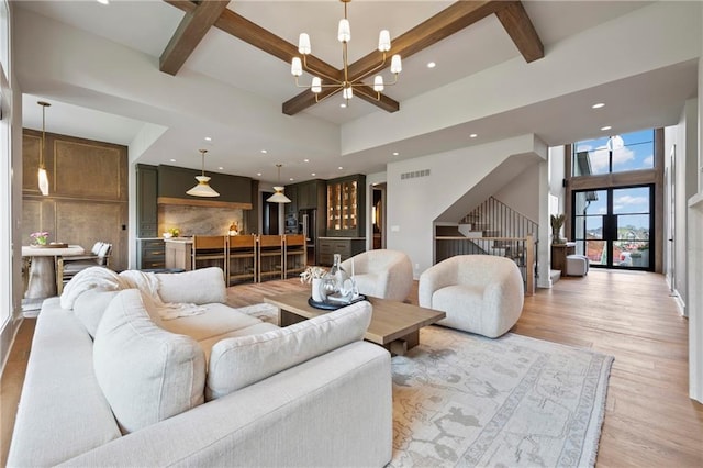 living area with visible vents, stairway, beamed ceiling, a chandelier, and light wood-style flooring