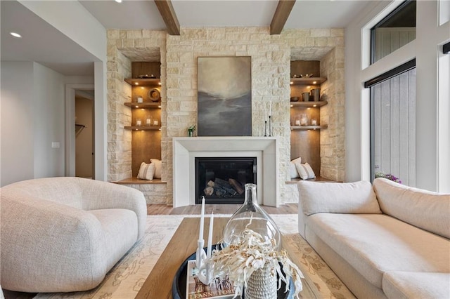 living room featuring beam ceiling, a glass covered fireplace, and wood finished floors