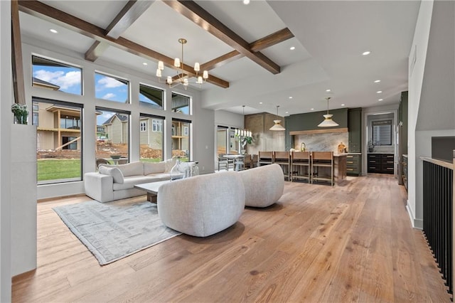 living area featuring light wood-style floors, coffered ceiling, and a healthy amount of sunlight