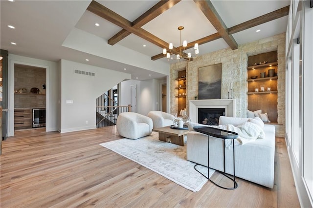 living room with visible vents, a glass covered fireplace, baseboards, coffered ceiling, and light wood-style flooring