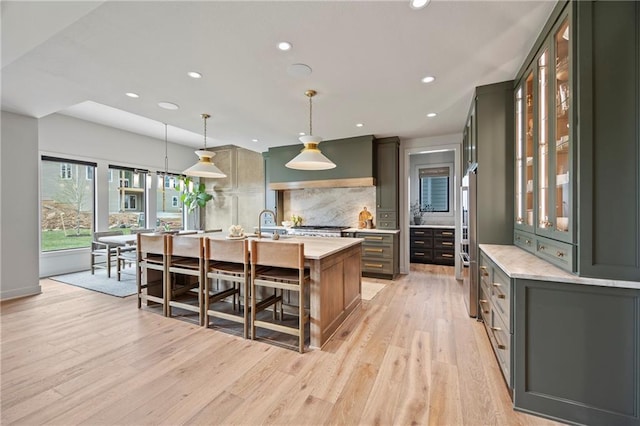 kitchen featuring a kitchen island with sink, recessed lighting, decorative backsplash, and light wood finished floors