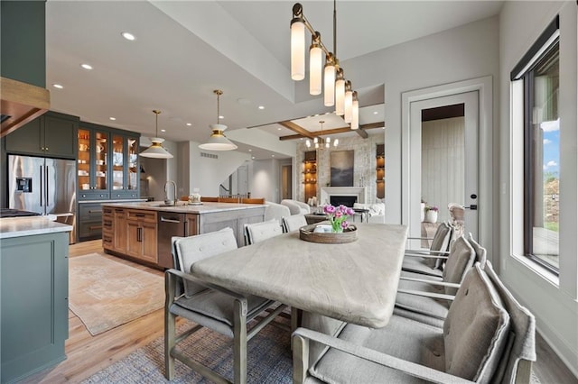 dining room featuring light wood-type flooring, recessed lighting, and a fireplace