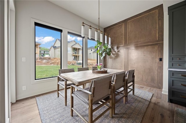 dining space with baseboards, visible vents, and light wood-type flooring