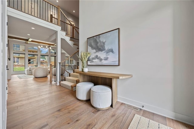 staircase with baseboards, recessed lighting, a towering ceiling, and wood finished floors