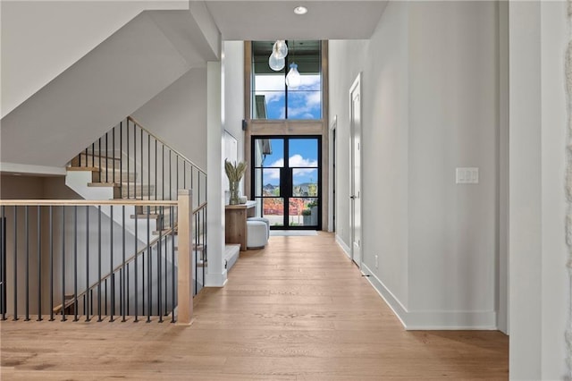 hall with baseboards, a high ceiling, an upstairs landing, and wood finished floors