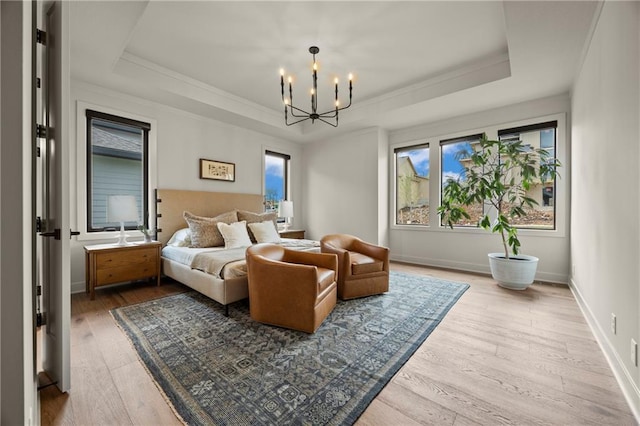 bedroom with a raised ceiling, ornamental molding, wood finished floors, and a notable chandelier