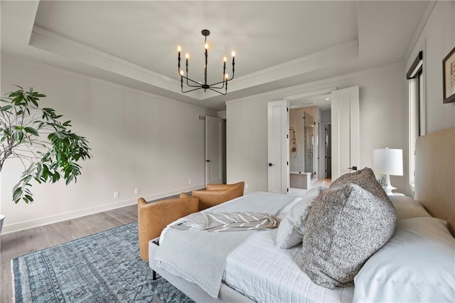 bedroom with an inviting chandelier, crown molding, a tray ceiling, and wood finished floors