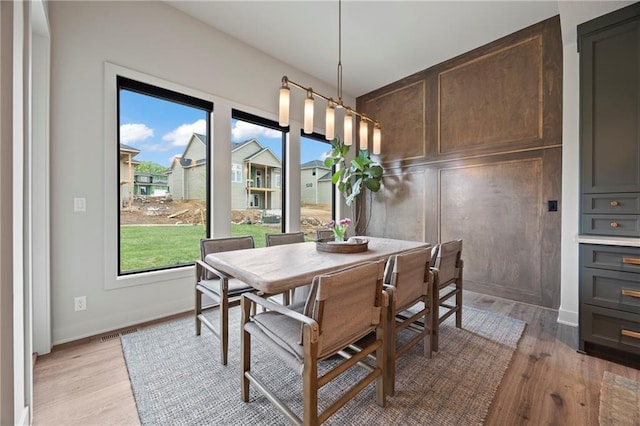 dining space with baseboards, light wood-style flooring, and visible vents