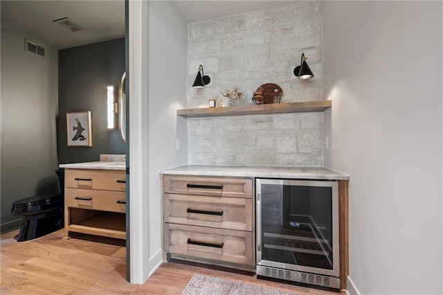 bar featuring visible vents, decorative backsplash, wine cooler, light wood-type flooring, and a bar