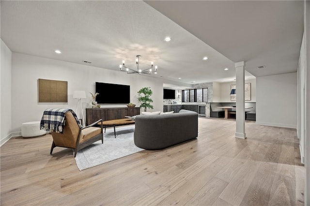 living area featuring recessed lighting, decorative columns, and light wood-style floors