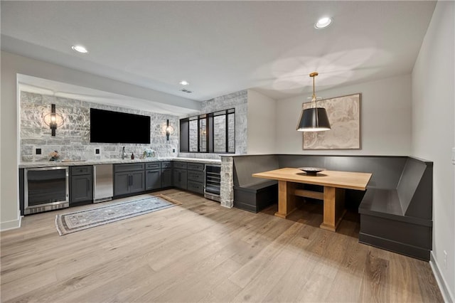 bar featuring indoor wet bar, beverage cooler, refrigerator, and light wood-type flooring