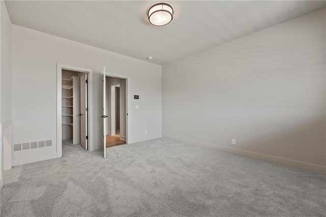 unfurnished bedroom featuring visible vents, carpet floors, baseboards, a closet, and a spacious closet