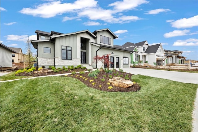 view of front facade featuring driveway, a front yard, a residential view, a garage, and stone siding