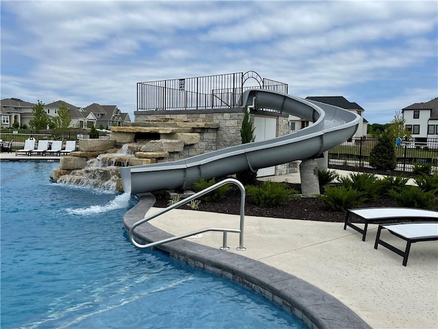 pool with fence, a water slide, a residential view, and a patio area
