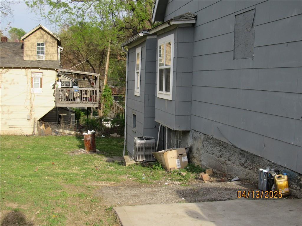 view of side of property featuring a yard, central AC unit, and a wooden deck