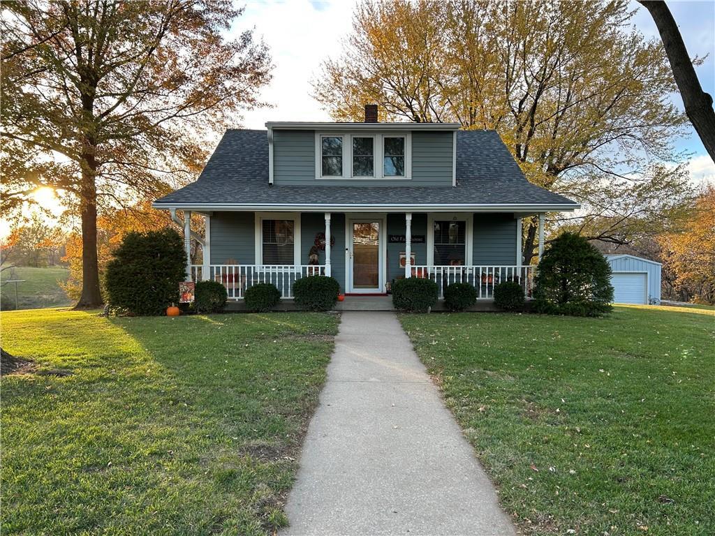 bungalow with a chimney, covered porch, a front lawn, and a shingled roof
