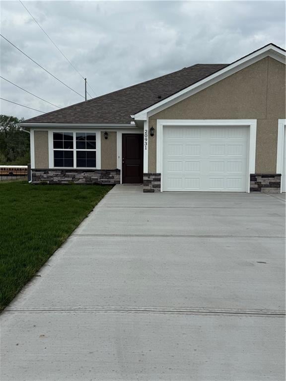 view of front of property featuring a garage, stucco siding, stone siding, and concrete driveway