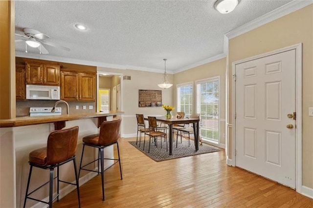 kitchen with a textured ceiling, white microwave, and brown cabinets