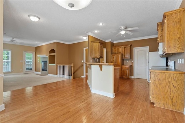 kitchen with brown cabinets, a breakfast bar area, a ceiling fan, and a peninsula