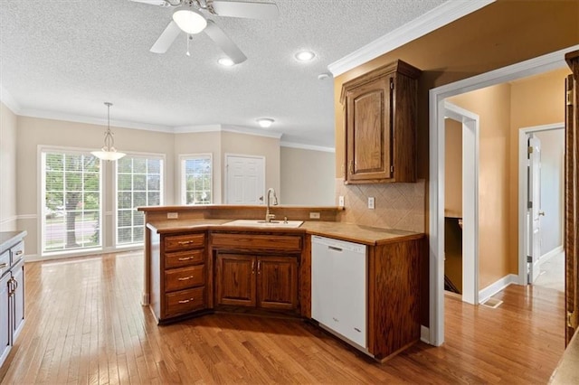 kitchen featuring a textured ceiling, a sink, light wood finished floors, and dishwasher