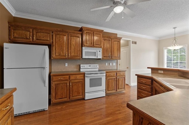 kitchen with white appliances, brown cabinets, crown molding, and wood finished floors