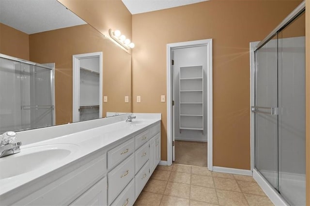 full bathroom featuring a spacious closet, a sink, and a stall shower