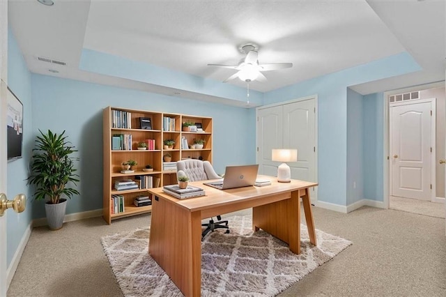 office with baseboards, visible vents, ceiling fan, and light colored carpet