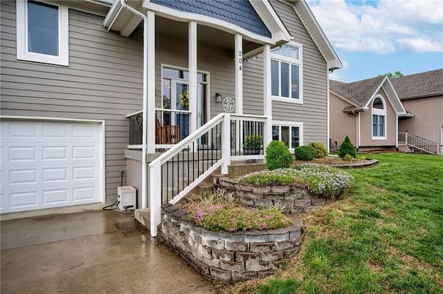 view of exterior entry with an attached garage, a yard, and concrete driveway