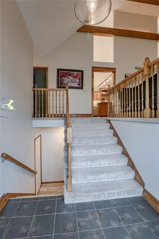 staircase featuring baseboards and high vaulted ceiling