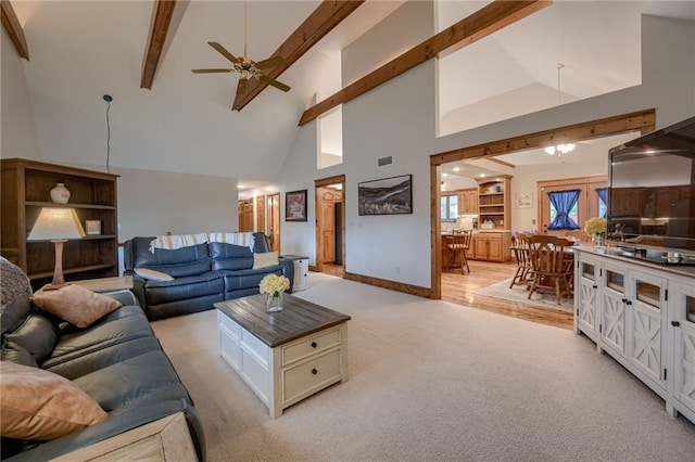 living area featuring beam ceiling, baseboards, high vaulted ceiling, light colored carpet, and a ceiling fan