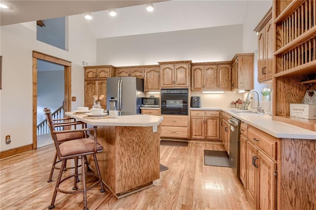 kitchen with a sink, appliances with stainless steel finishes, high vaulted ceiling, and light countertops